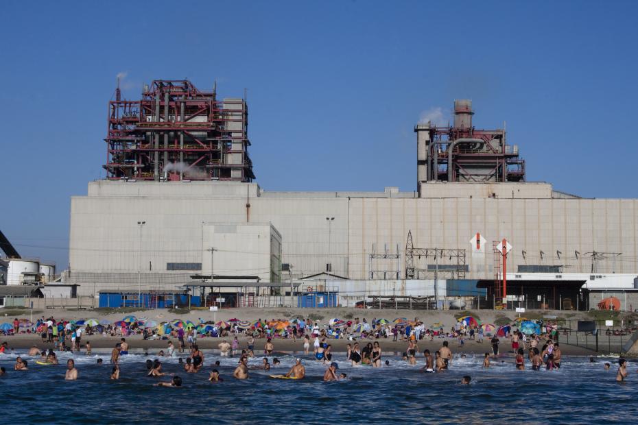 Gente en la playa de Puchuncaví, Chile, con la Fundición Ventanas detrás.