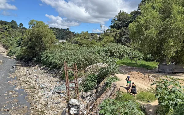 mujeres en Guatemala caminando junto a un río contaminado.